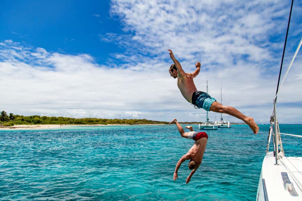 Zwei Segler springen ins türkisfarbene Karibik-Meerwasser