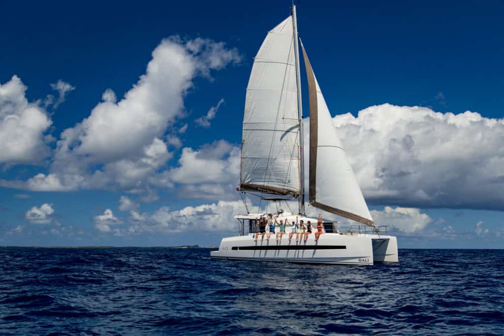 Katamaran mit Crew an Deck vor strahlend blauem Himmel