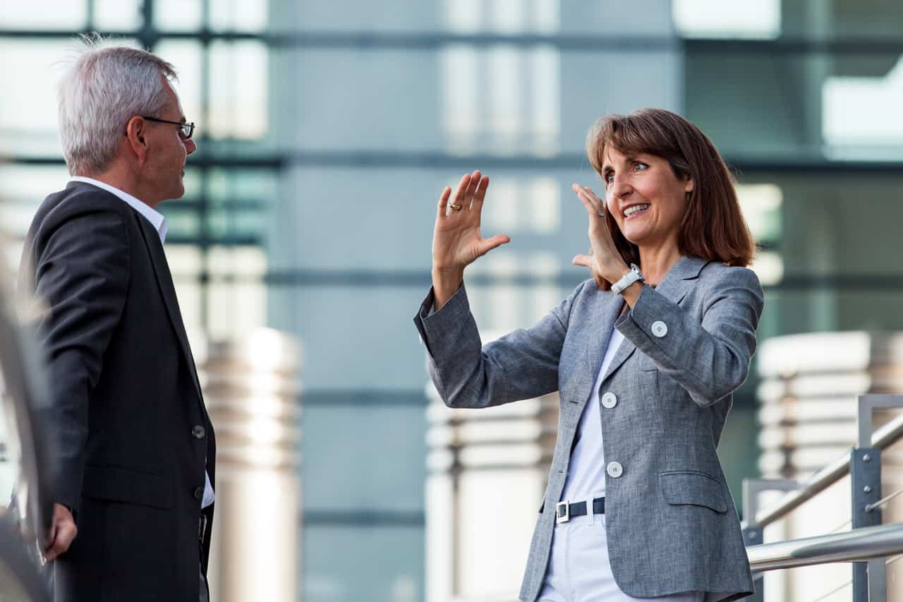 Business Portrait Gesprächssituation Geschäftsfrau und Geschäftsmann vor Glas-Stahl-Wand