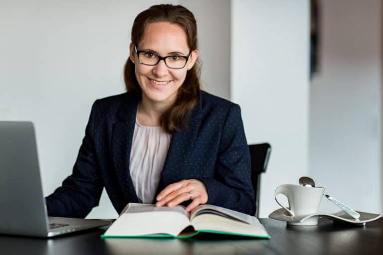 Übersetzerin mit Wörterbuch, Laptop und Kaffeetasse