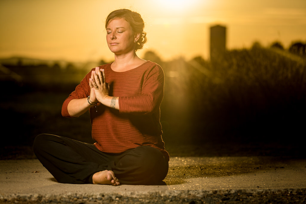 Yoga-Lehrer im Schneidersitz im Sonnenuntergang